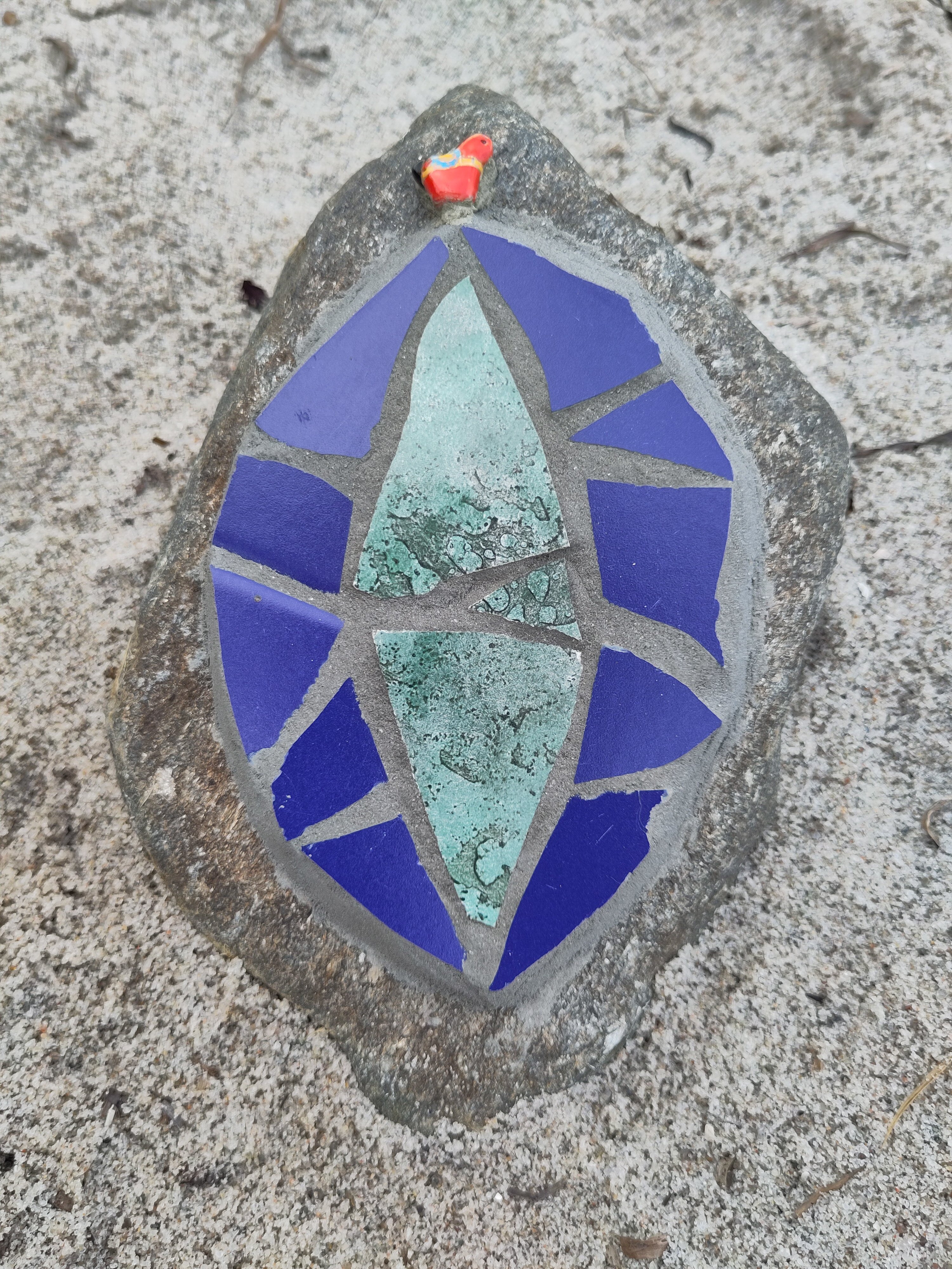 Strandsten med mosaik. Hellig portal. Blågrøn med blå kant og rød perle.Lotte Rosenkilde.